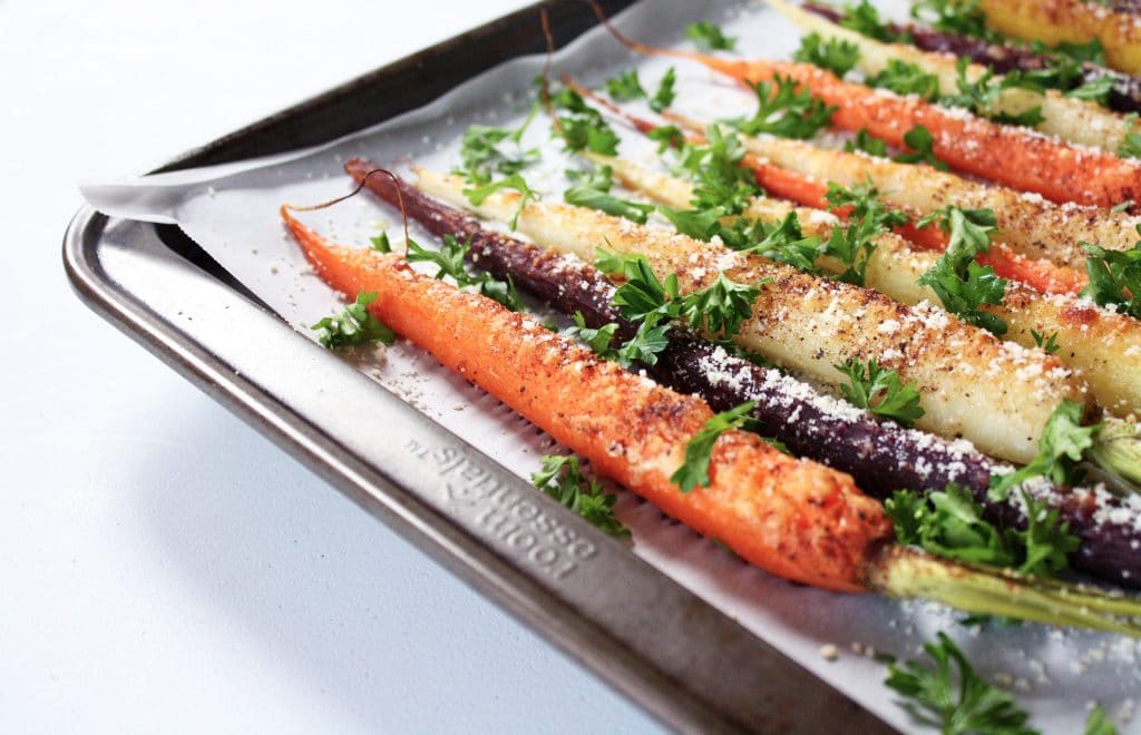 side angle shot of rainbow carrots garnished with parsley and parmesan cheese