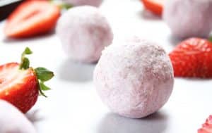 Strawberries-and-Cream-Fat-Bombs beside fresh halved strawberries