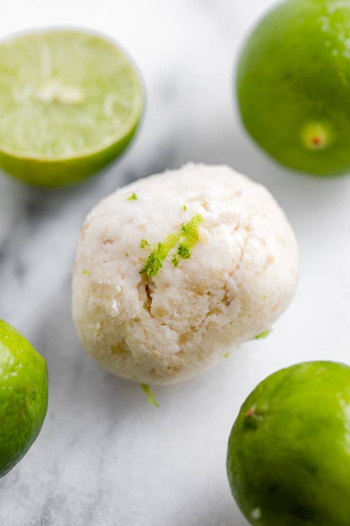 hero shot of key lime pie fat bomb beside halved limes atop a marble kitchen counter