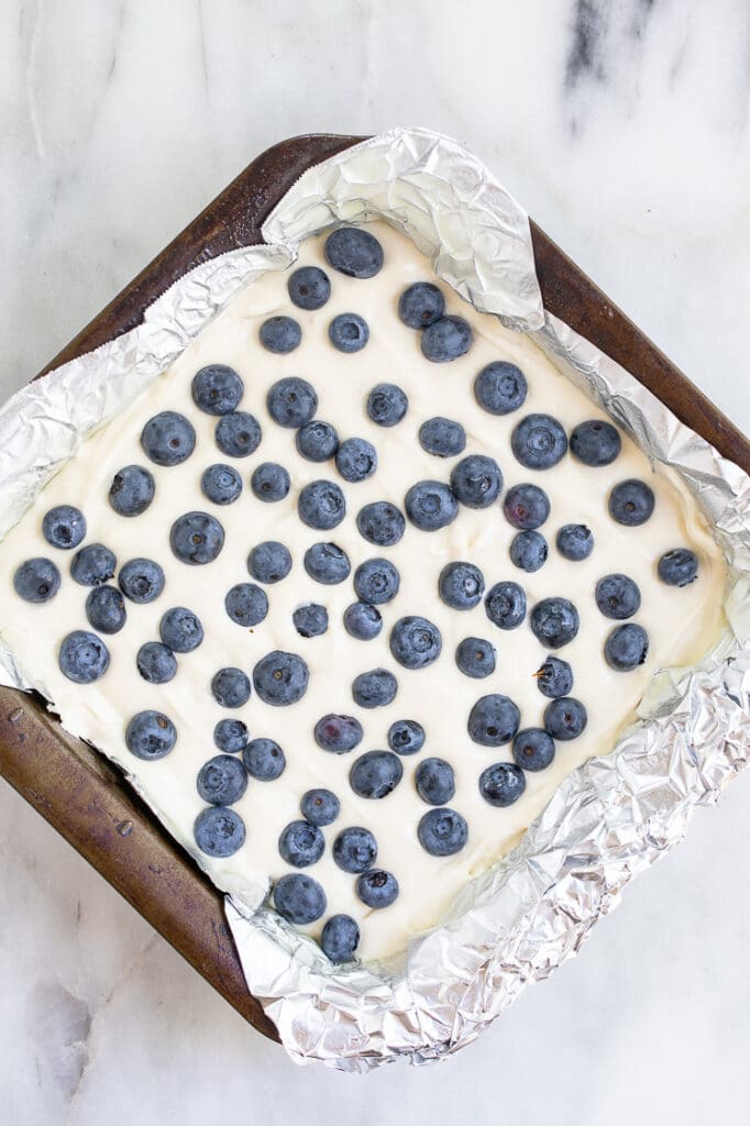 low-carb blueberry cheesecake batter with blueberries on top in a baking pan