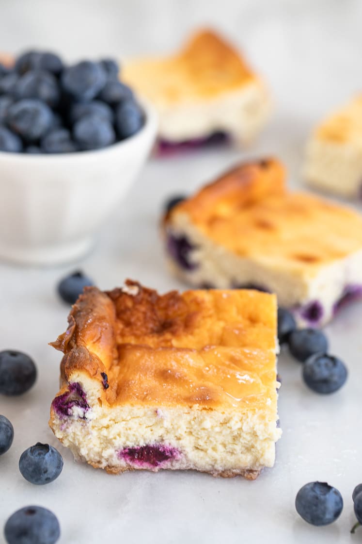 deliciously creamy cheesecake bars with blueberries atop a marble kitchen counter