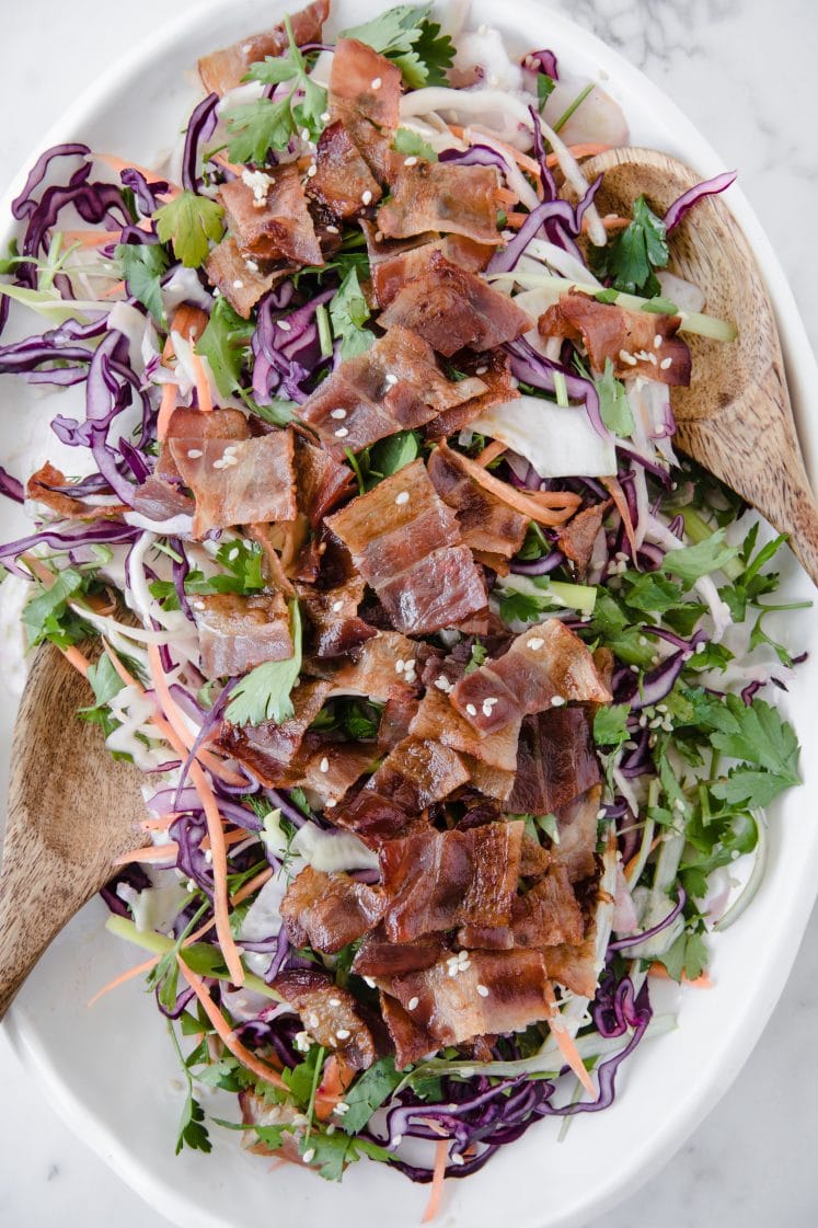overhead shot of a keto bacon salad atop a marble kitchen counter with a wooden serving spoon