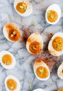 overhead-shot-of-buffalo-deviled-eggs-on-marble-board garnished with paprika