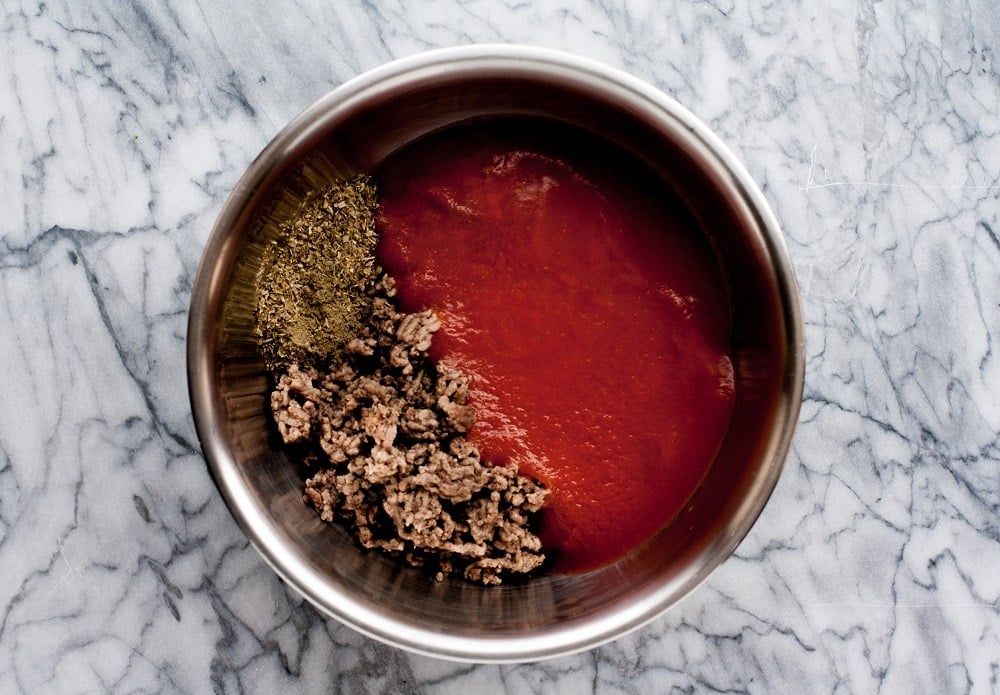 tomato-sauce-spices-and-beef-in-stainless-steel-bowl-on-marble-board-for-Low-Carb-Zucchini-Pizza-Casserole