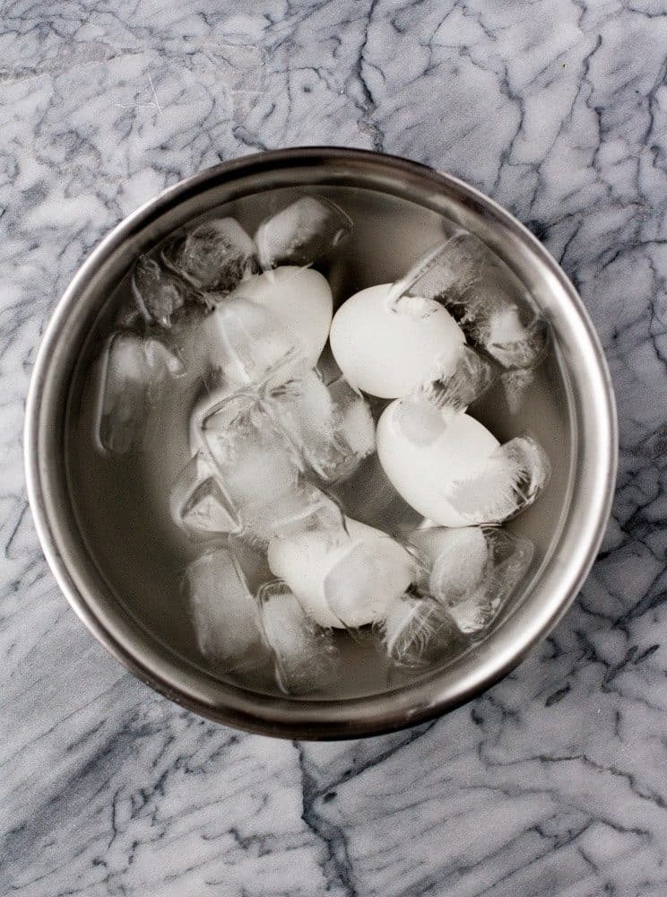 hard-boiled-eggs-in-ice-bath-in-stainless-steel-bowl-on-marble-kitchen-counter