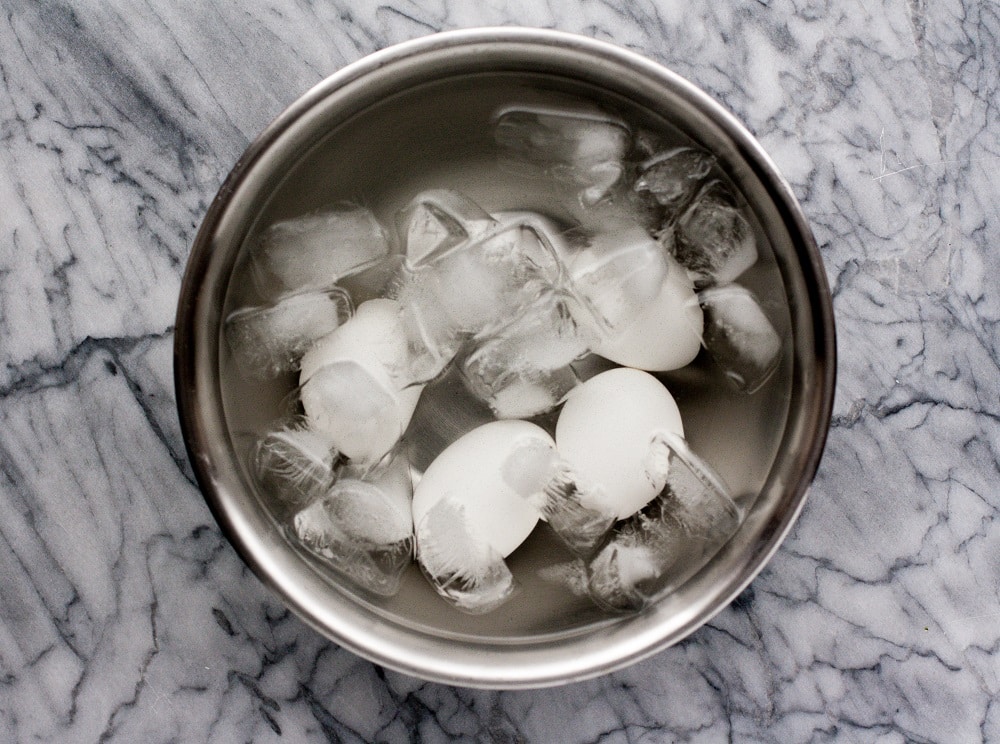 hard-boiled-eggs-in-ice-bath-in-stainless-steel-bowl-on-marble-board-for-warm-bacon-and-egg-salad