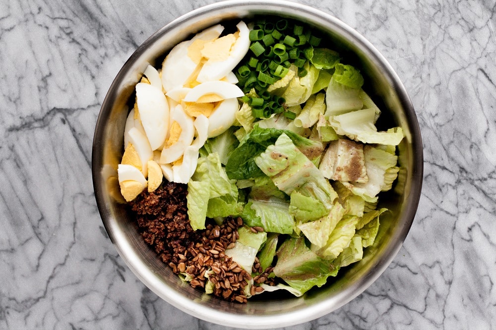ingredients-for-warm-bacon-and-egg-salad-in-stainless-steel-bowl-on-marble-board