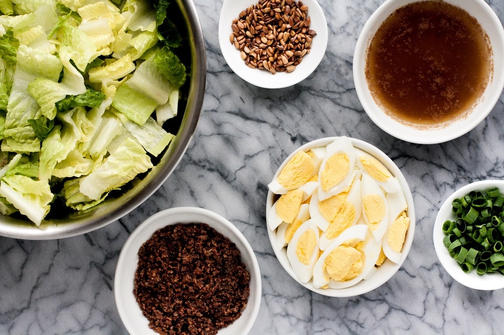 ingredients-for-warm-bacon-and-egg-salad-in-separate-bowls-on-marble-board