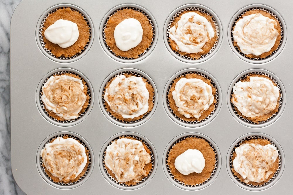 overhead-shot-of-Cream-Cheese-Pumpkin-Muffins-dough-with-cream-cheese-swirl-in-muffin-tin-on-marble-board