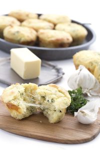 Keto Side Dish Recipes - cheesy garlic bread muffin broken in half beside garlic cloves and butter