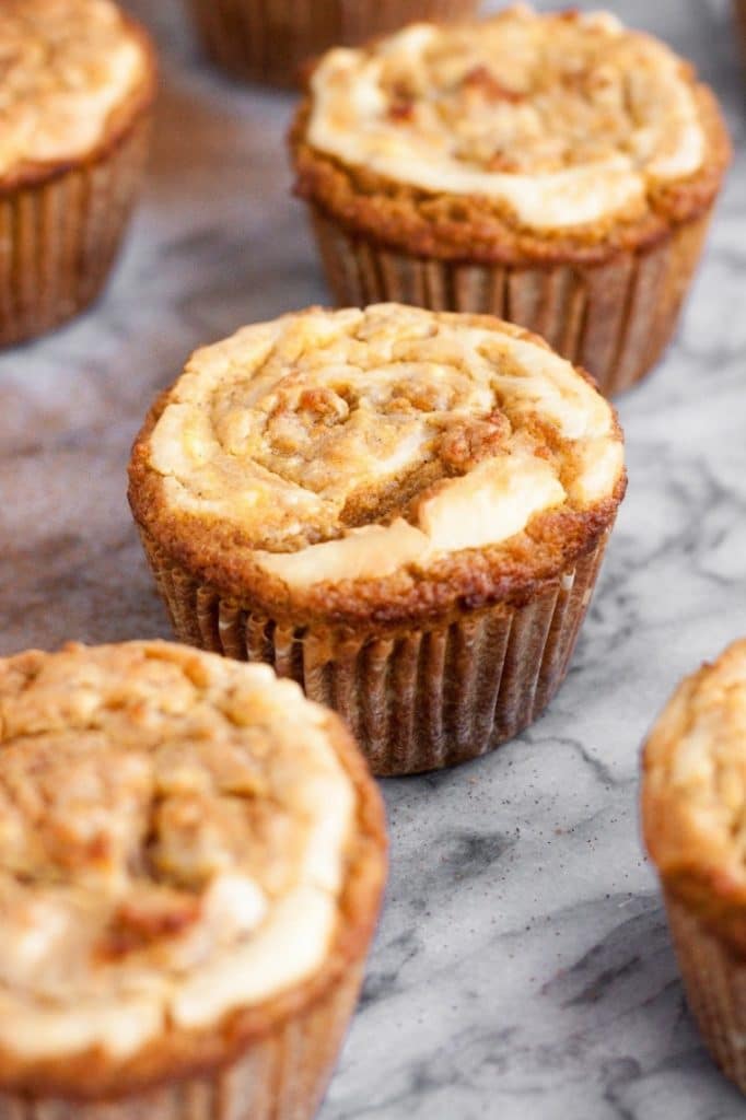 side angle shot of baked cream cheese pumpkin muffins on marble countertop