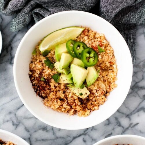 close-up-overhead-shot-of-mexican-cauliflower-rice-in-white-bowls-on-marble-board