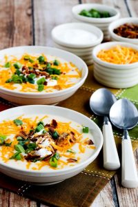 instant pot low carb loaded cauliflower soup in bowls beside spoons and garnish options