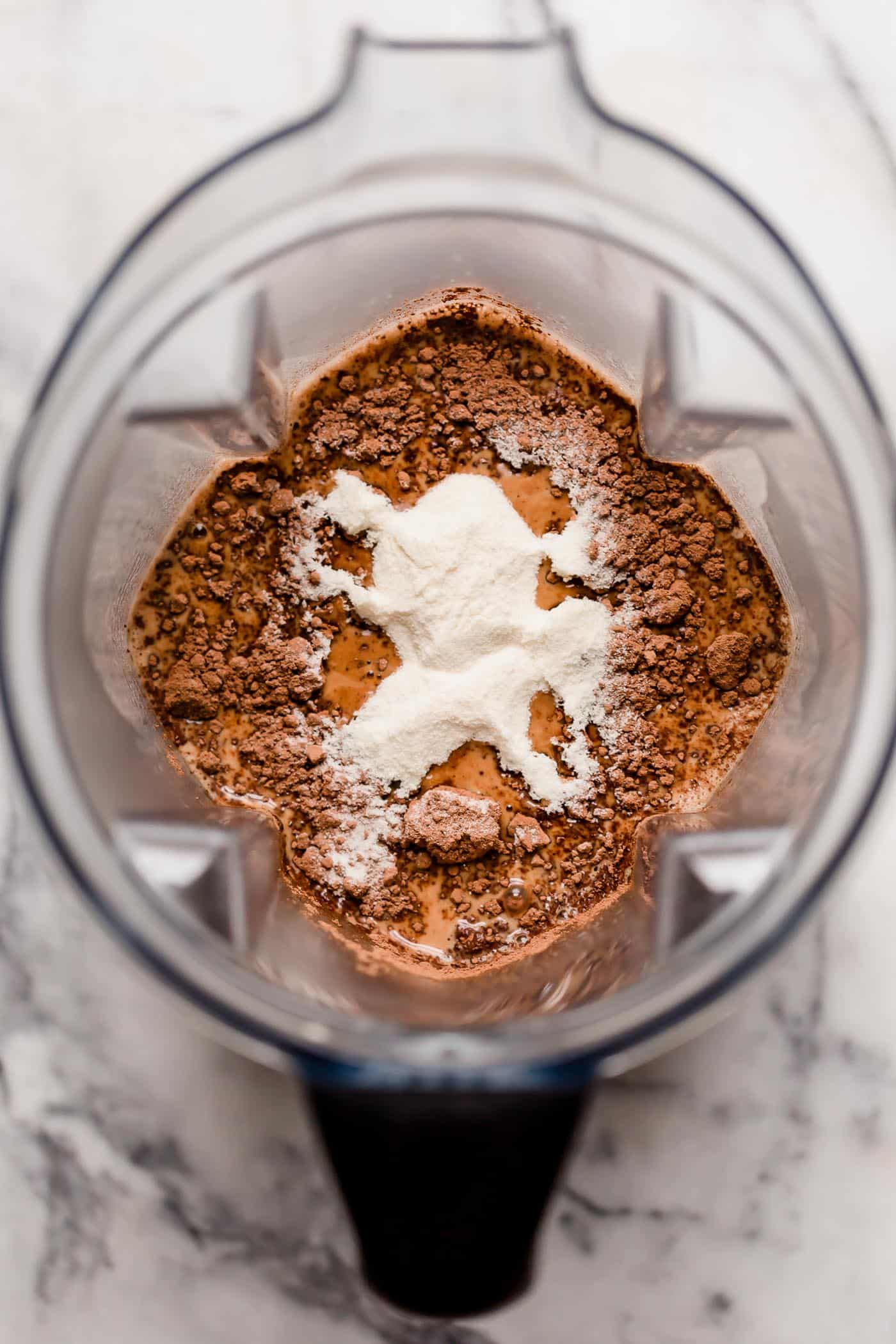 overhead shot of hot coffee with cream, unsweetened cocoa powder, collagen powder, MCT oil powder, and lakanto monk fruit sweetener