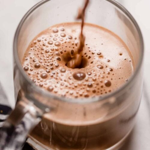 a serving of bulletproof peppermint mocha poured in a clear glass mug on top of a marble counter