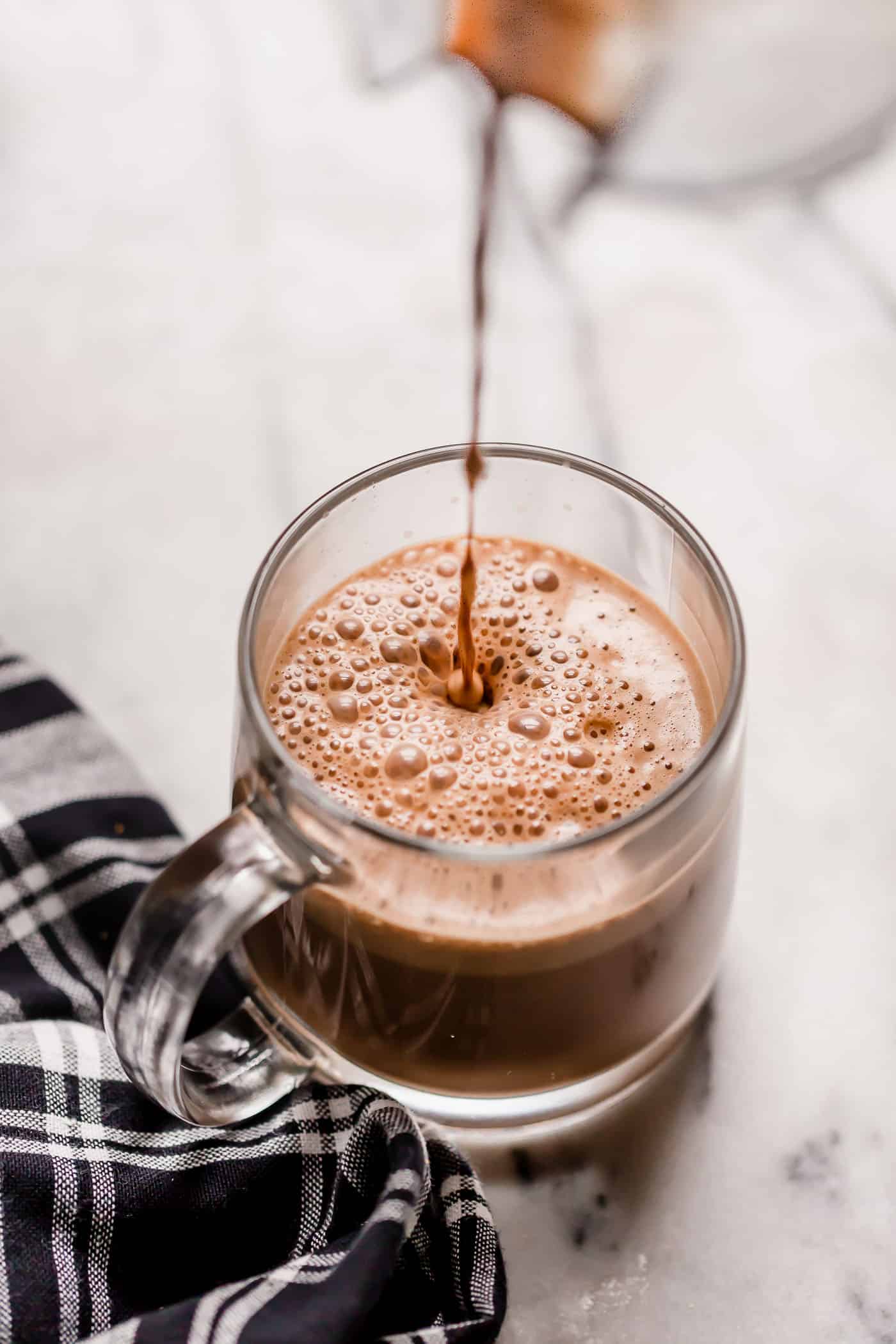 Bulletproof Peppermint Mocha poured into a clear glass mug on top of a marble counter