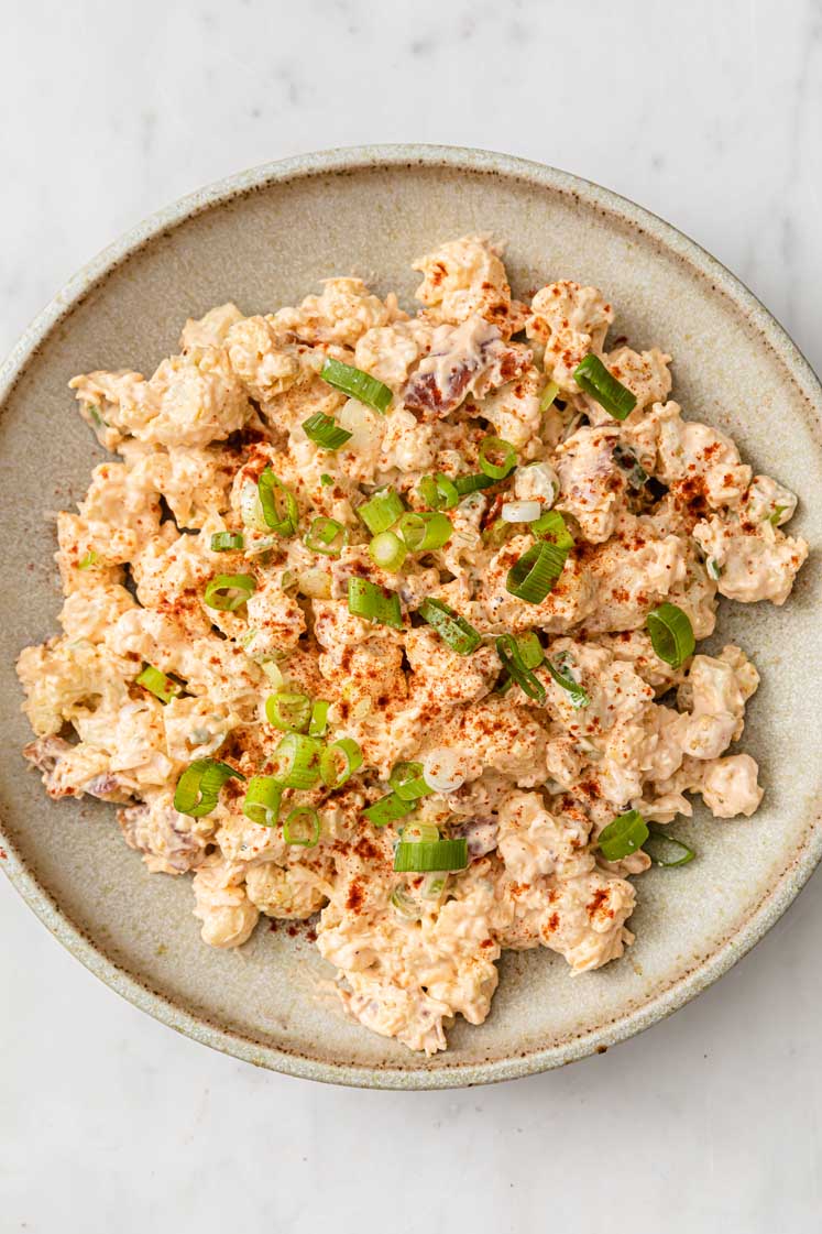 overhead image of a plate of cauliflower potato salad atop a marble kitchen counter