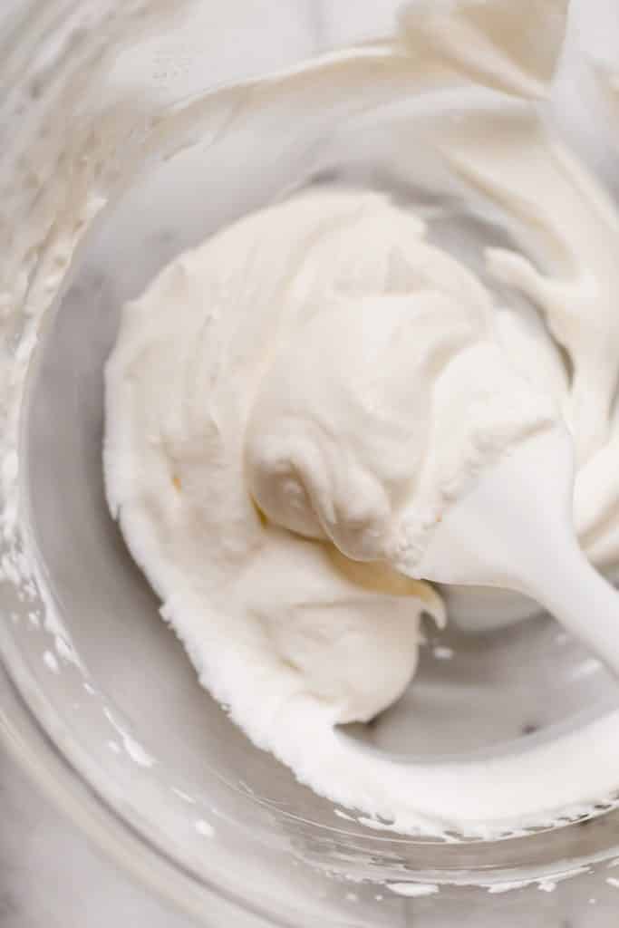glass bowl of homemade whipped cream with white spatula