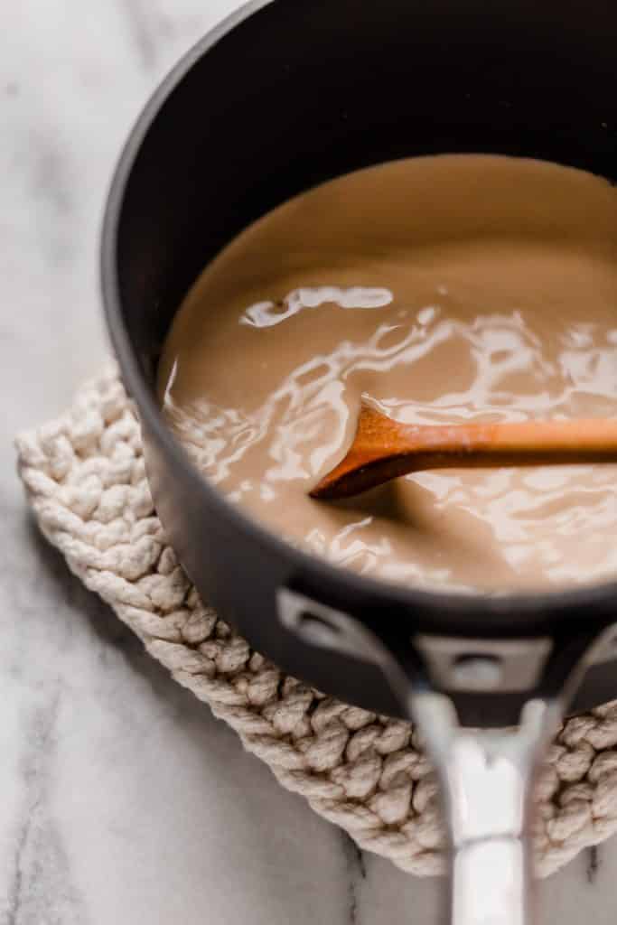 stirring small pot of cinnamon dolce latte with a wooden spoon