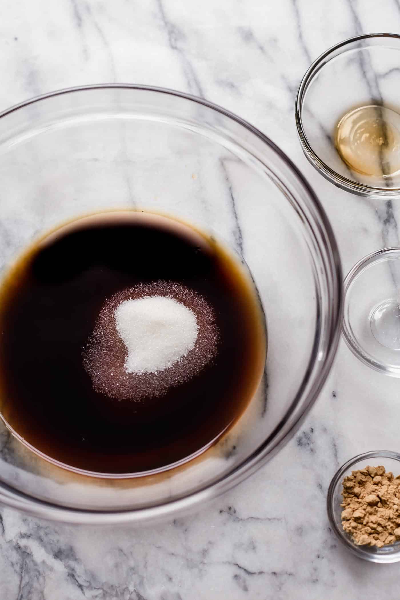 beef broth, liquid aminos, ground ginger, monk fruit sweetener in individual bowls on top of a marble table
