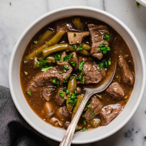 hero shot of instant pot beef stew in a ceramic bowl with a spoon
