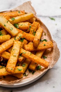 Golden Jicama Fries on a plate garnished with chopped parsley 