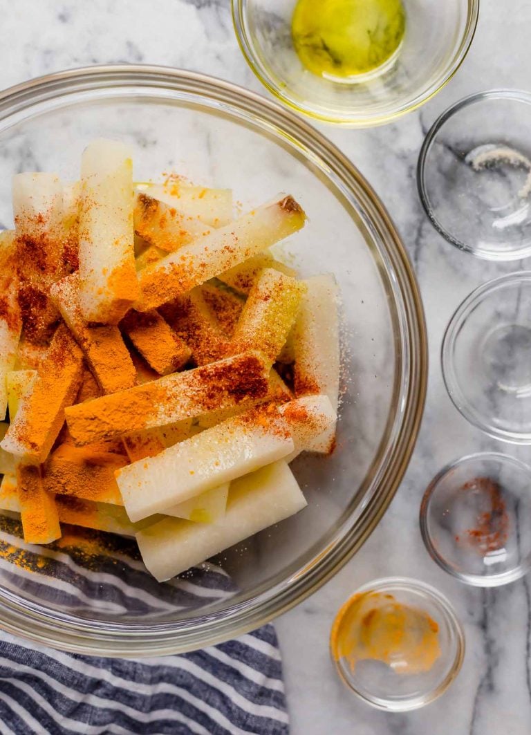 jicama fries in a large bowl with spices poured in