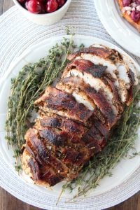 a log of Garlic Herb Bacon Wrapped Turkey Breast on a plate
