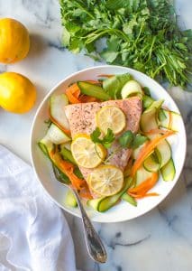 instant pot lemon garlic salmon on a plate with veggies beside parsley and lemons