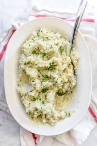Mashed Cauliflower with Parmesan and Chives in a ceramic serving plate with serving spoon