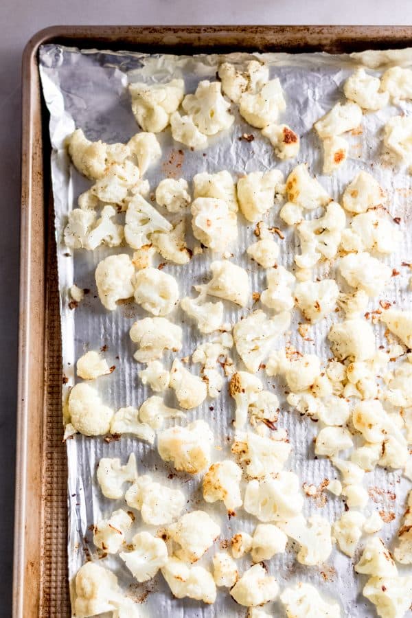 Overhead shot of baked cauliflower florets on foil-lined baking sheet after being baked