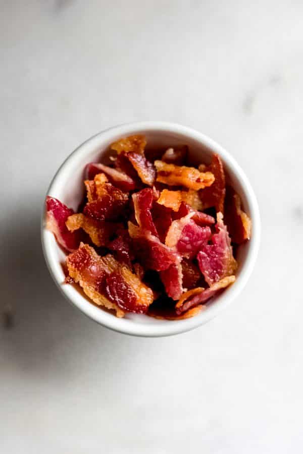 Overhead shot of crumbled bacon in bowl on marble board