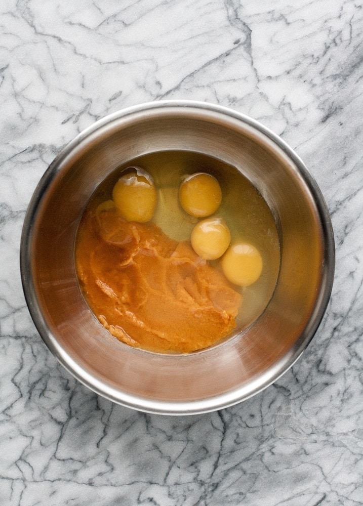 four eggs pumpkin puree and vanilla extract in a stainless steel mixing bowl