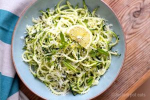 10-minute zucchini noodles with garlic lemon and parmesan on a plate atop a wooden table