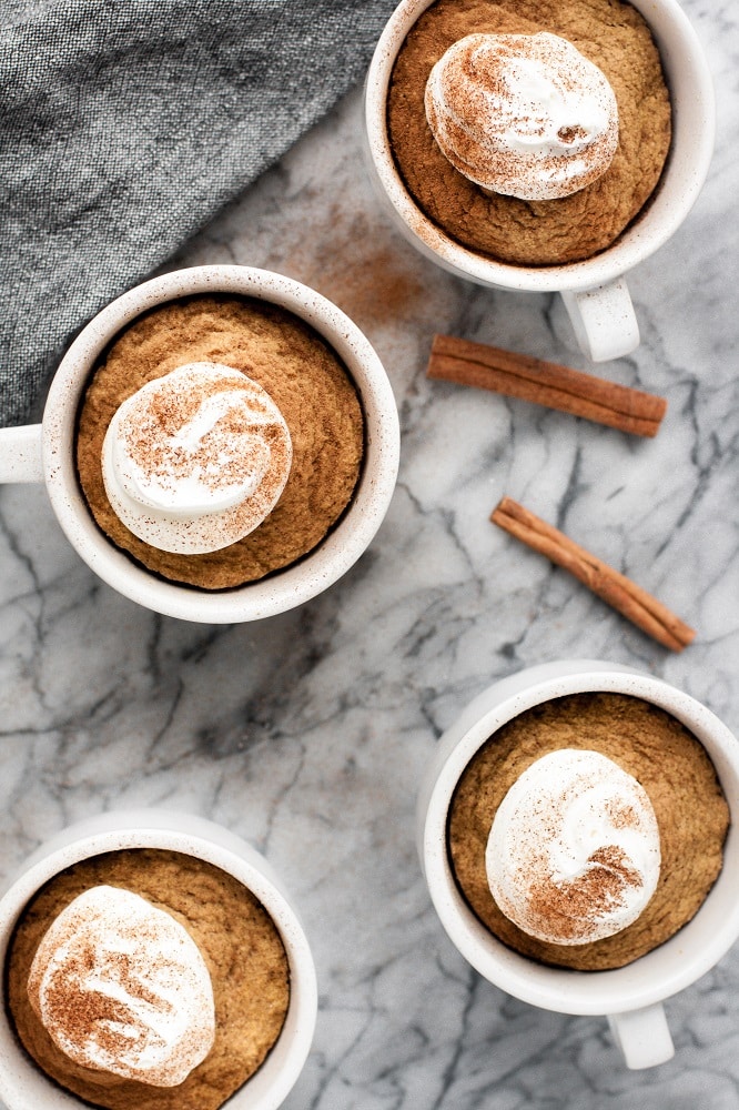 keto pumpkin pie mug cake with dollop of whipped cream and cinnamon