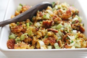 keto stuffing in a square ceramic bowl with a wooden serving spoon