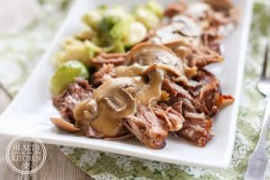 low carb pork roast with mushroom gravy on a rectangular ceramic dish served with brussel sprouts