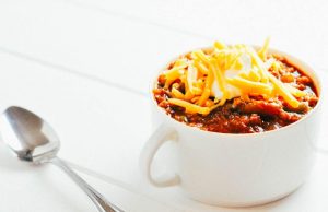 tomatillo chili in a mug beside a spoon