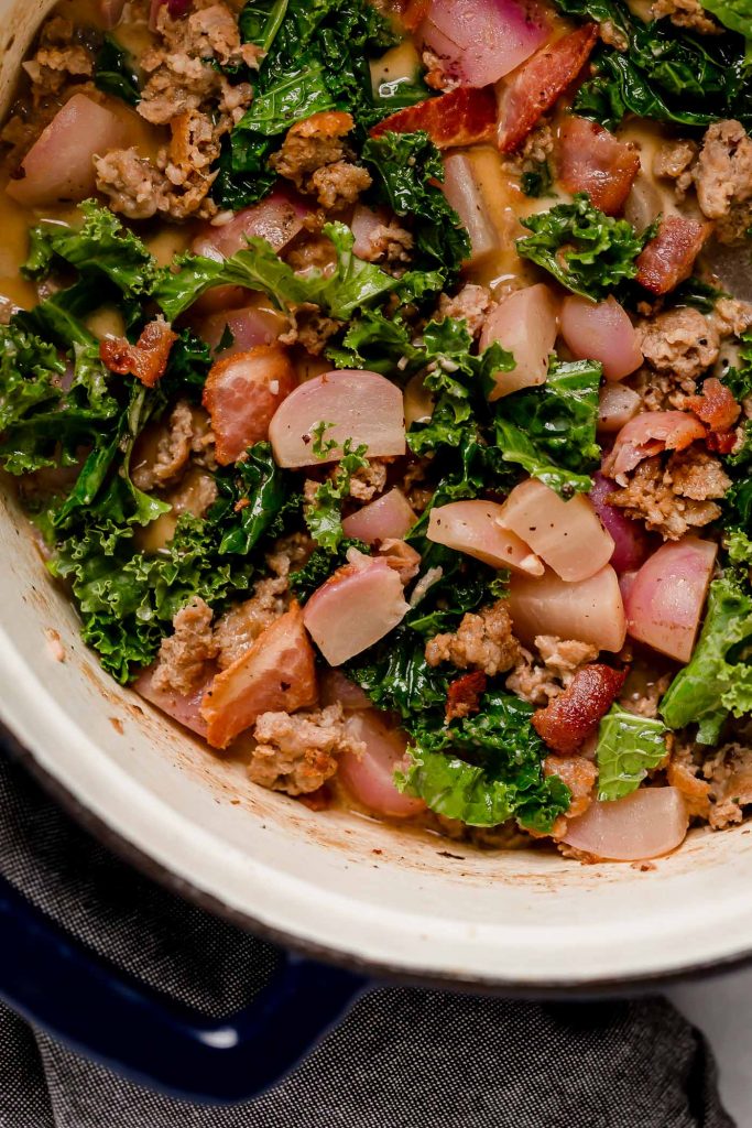 simmered soup mixed in with chopped kale, wilted, and browned sausage