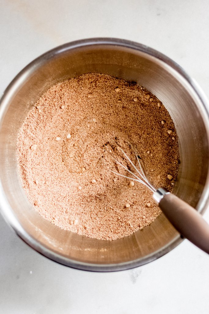 dry ingredients for keto gingerbread cookie dough whisked together in a large stainless steel mixing bowl