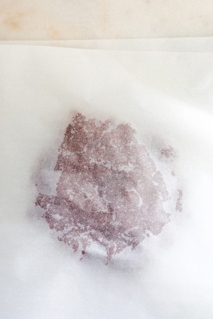 chilled keto gingerbread cookie dough in between two sheets of parchment paper sprayed with nonstick cooking spray