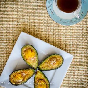 4 Baked Eggs in Avocados on a plate with cup of tea