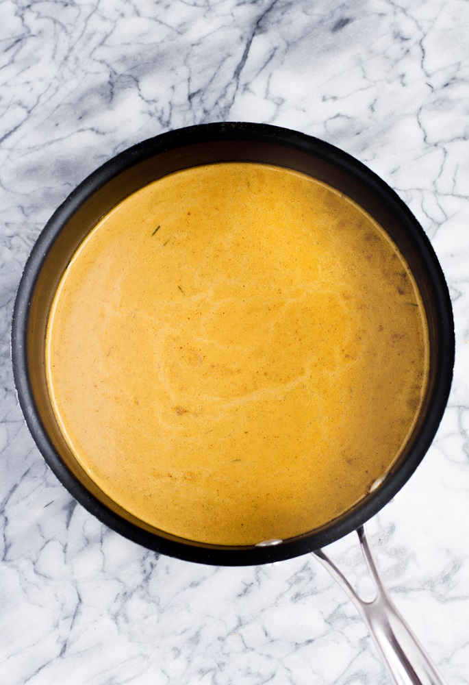 pumpkin sunbutter soup in a large pot atop a marble counter