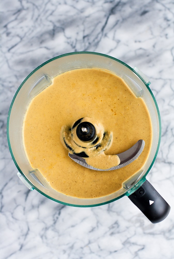 pumpkin sunbutter soup poured in a food processor on top of a marble kitchen counter