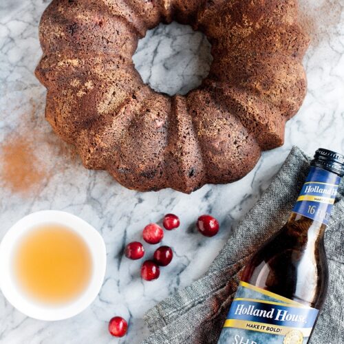Low Carb Chocolate Cranberry Bundt Cake with Sherry Cooking Wine on top of a marble counter beside cranberries and holland house cooking wine