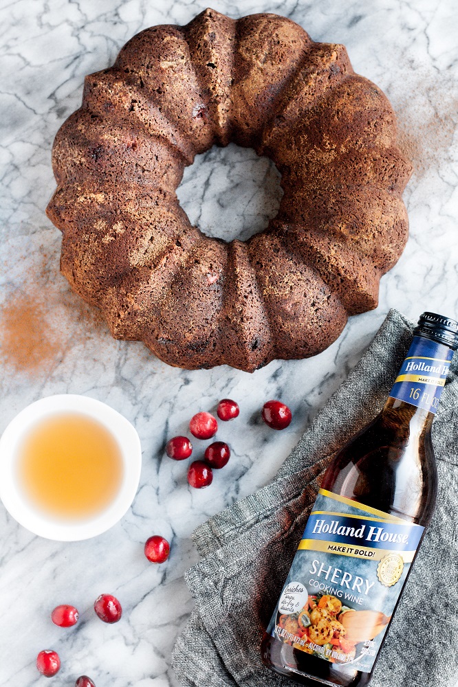 Low Carb Chocolate Cranberry Bundt Cake with Sherry Cooking Wine on top of a marble counter beside cranberries and holland house cooking wine
