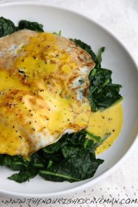 Close-up of Kale and Eggs Benedict on a white plate