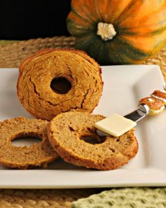 Plate of low carb pumpkin bagels with one sliced with butter