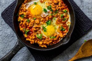 Skillet of Keto turkey and Egg Breakfast skillet on black cloth with wooden spoon