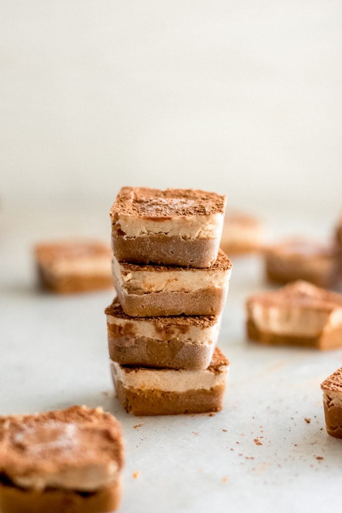 recipe hero shot - four tiramisu stacked together beside scattered pieces of tiramisu fat bombs